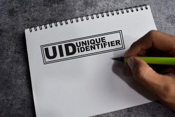 Concept of UID - Unique Identifier write on book isolated on Wooden Table.