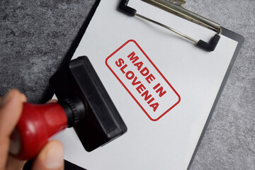 Red Handle Rubber Stamper and Made in Slovenia text above clipboard isolated on wooden background