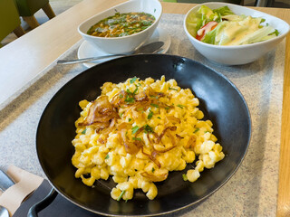 Cheesy german spaetzle with crispy onions and fresh salad on a tray