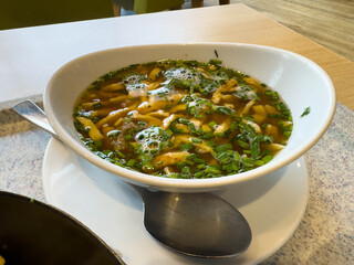 Fresh chicken soup with herbs in ceramic bowl