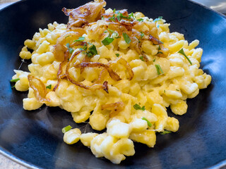 Delicious german spaetzle with caramelized onions and chives in black bowl