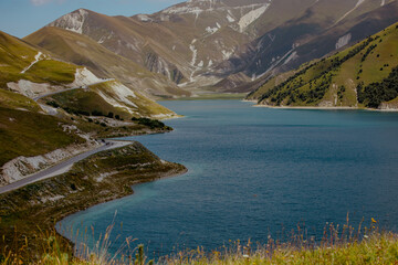 Aerial view of a serene lake surrounded by lush green hills in the Caucasus region. Clear blue...