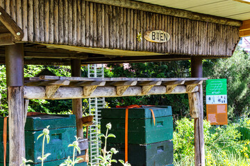 Shed with wooden beehives or apiaries,green vegetation in background, plaque with inscription...