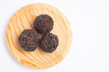 Three chocolate truffles covered with chocolate sprinkles served on a round wooden plate isolated on white background.