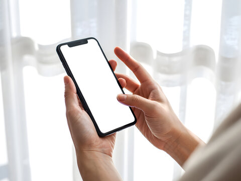 Hand holding smartphone with blank screen isolated in natural light background for app mockup and design presentation.