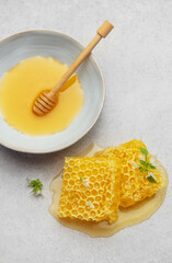 Honeycomb, honey dipper and bowl of honey on kitchen table