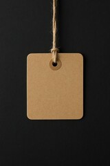 A realistic brown kraft paper tag mockup hanging on rustic twine against a dark textured paper background. Perfect for showcasing branding, identity, retail, price labels, or product design