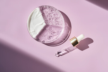 Pipettes and texture of cosmetic products in a petri dish on a purple background.