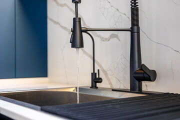 Title: Black faucet. Water stream. Blue kitchen
