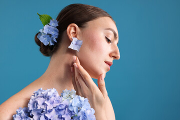Beautiful young woman with hortensia flowers on blue background