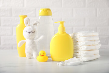 Many different baby accessories and toy bunny on table near brick wall