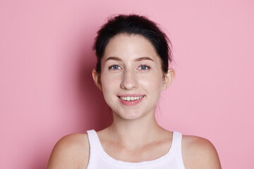 Portrait of smiling woman after dental aligners treatment on pink background