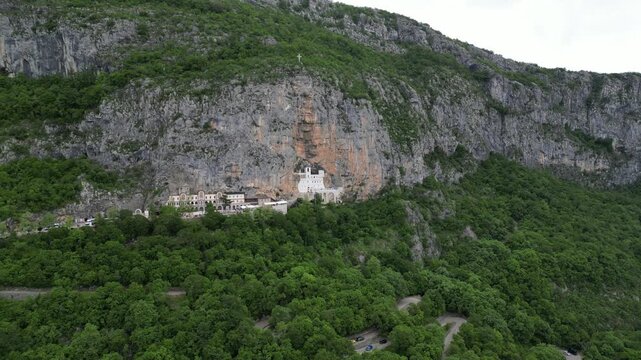 Cinematic aerial drone footage of Ostrog Monastery Montenegro panoramic horizontal view from left to right with mountains in background