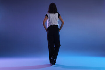 Teenage girl in tap shoes dancing on color background, back view