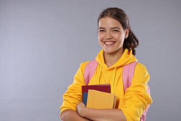 Obraz premium Student with notebooks happy about her good exam result on gray background