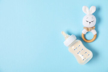 Feeding bottle with formula and teether on light blue background, flat lay. Space for text