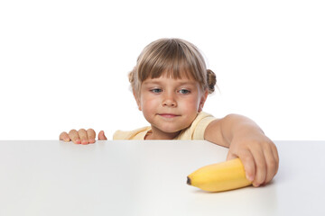 Cute little girl reaching for banana at table against white background