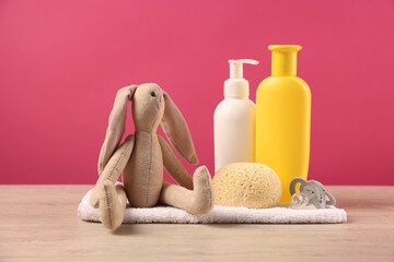 Baby accessories and bathing products on wooden table against pink background
