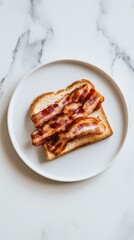 Sliced crispy bacon rests on toasted bread on a simple white plate in a clean kitchen environment