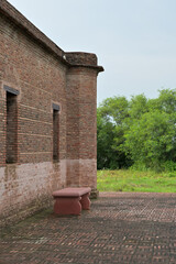 Brick building with old-world charm featuring a protruding round corner and rectangular windows without glass.
