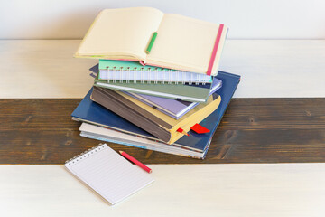 Stack of different books and open notebook on rustic table. Copy space