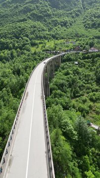 Vertical 4K drone video top-down flying forward over Đurđevića Tara Bridge tracking car crossing Tara River canyon Montenegro