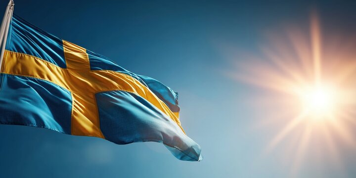 Swedish flag waving in bright sunlight against a clear blue sky