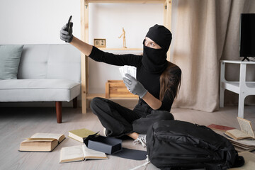 Female Burglar or thief stealing money from apartment taking self portrait with cash. Criminal,...