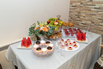 A delightful assortment of treats is displayed on a beautifully arranged table. Watermelon slices, pastries, and floral arrangements create a festive atmosphere perfect for celebration.