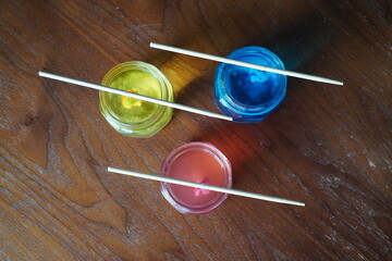 Colorful crystal growing science experiment in glass jars with red, yellow, and blue solutions, children’s STEM activity showing crystal formation process at home.