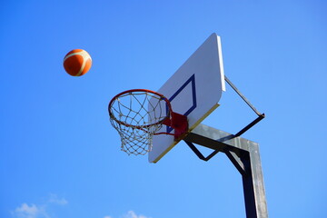 Basketball Flying Towards Hoop against Clear Blue Sky Capturing the Exciting Moment of Outdoor Sports and Active Lifestyle in Motion