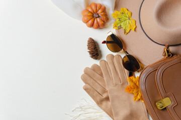 Autumn accessories flat lay. Brown hat, leather bag, gloves, shoes with pumpkins and colorful...