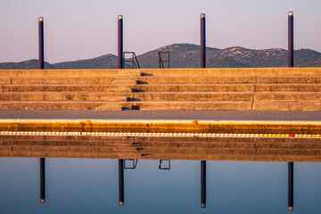 Concrete steps and stands of open air swimming pool in Biograd na Moru, Croatia, reflected in calm...