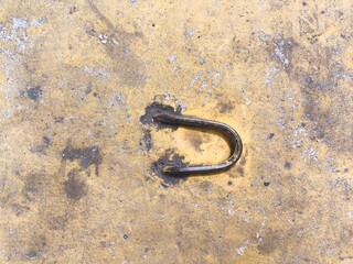 Rusty metal hook on weathered concrete wall surface