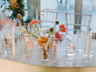 Elegant floral arrangement with candles on a dining table at a modern event venue during a daytime celebration