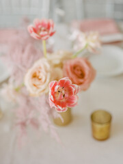 Beautiful floral arrangement featuring pink tulips and roses on a dining table for an elegant event
