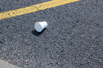 A Disposable Cup Carelessly Littered on the Asphalt Pavement