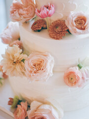Elegant three-tier wedding cake adorned with fresh flowers for a spring celebration in a bright venue