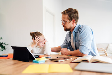 Girl looks up at father with frustration and confusion while working on tablet. Intimate digital learning moment showing tech fatigue and attentive parenting in home study setting.