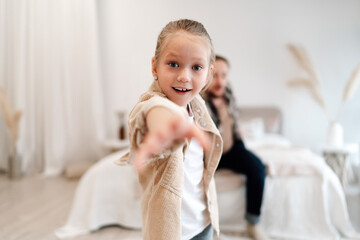 Fototapeta premium Father and daughter hold each other closely while smiling, gazing eye to eye on bed, reflecting strong emotional presence in modern family relationships.