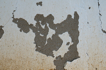 Peeling white paint on rough concrete wall
