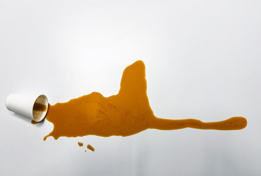 Accidental coffee spill on clean white surface top view representing morning rush deadline pressure and workplace distraction