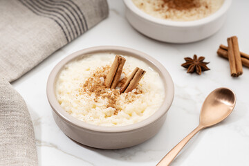 Creamy rice pudding with cinnamon in bowl on white marble table