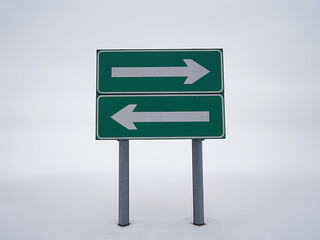 Green directional road sign with arrows pointing left and right