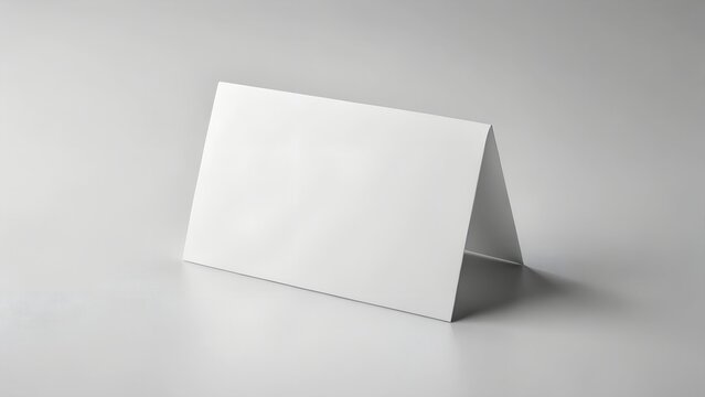 A blank white folded card stands on a white surface, isolated on white background, serving as a versatile template for place cards, greetings, or event messages with ample space for text