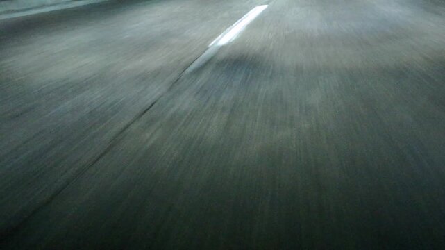 Low angle POV asphalt road with lane markings. Night