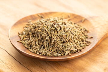 Cumin seeds on wooden spoon on table. Cuminum cyminum
