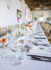 Banquet table in rustic European style. White tablecloth and empty glasses and plates..