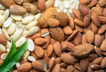 Large group of different almond nuts and almond leaves close-up. Food background.