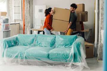 Happy couple carrying boxes into new apartment, moving day
